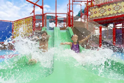 Children sliding down green water slides at Moon Palace The Grand Cancun.