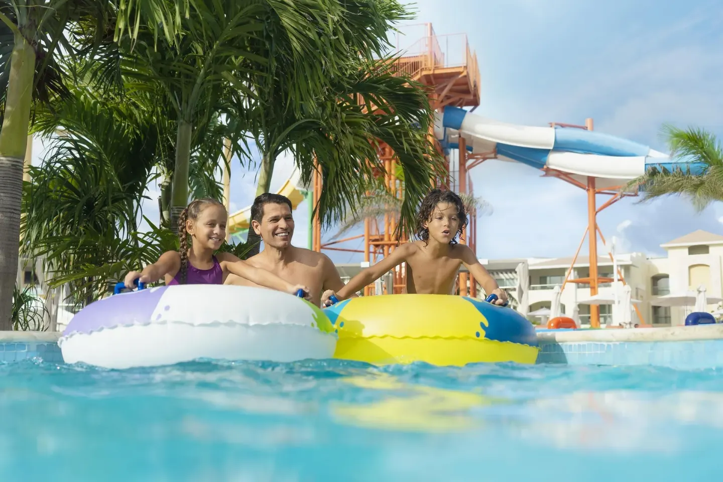 Family with pool floats near a tall waterslide at Moon Palace The Grand Cancun.
