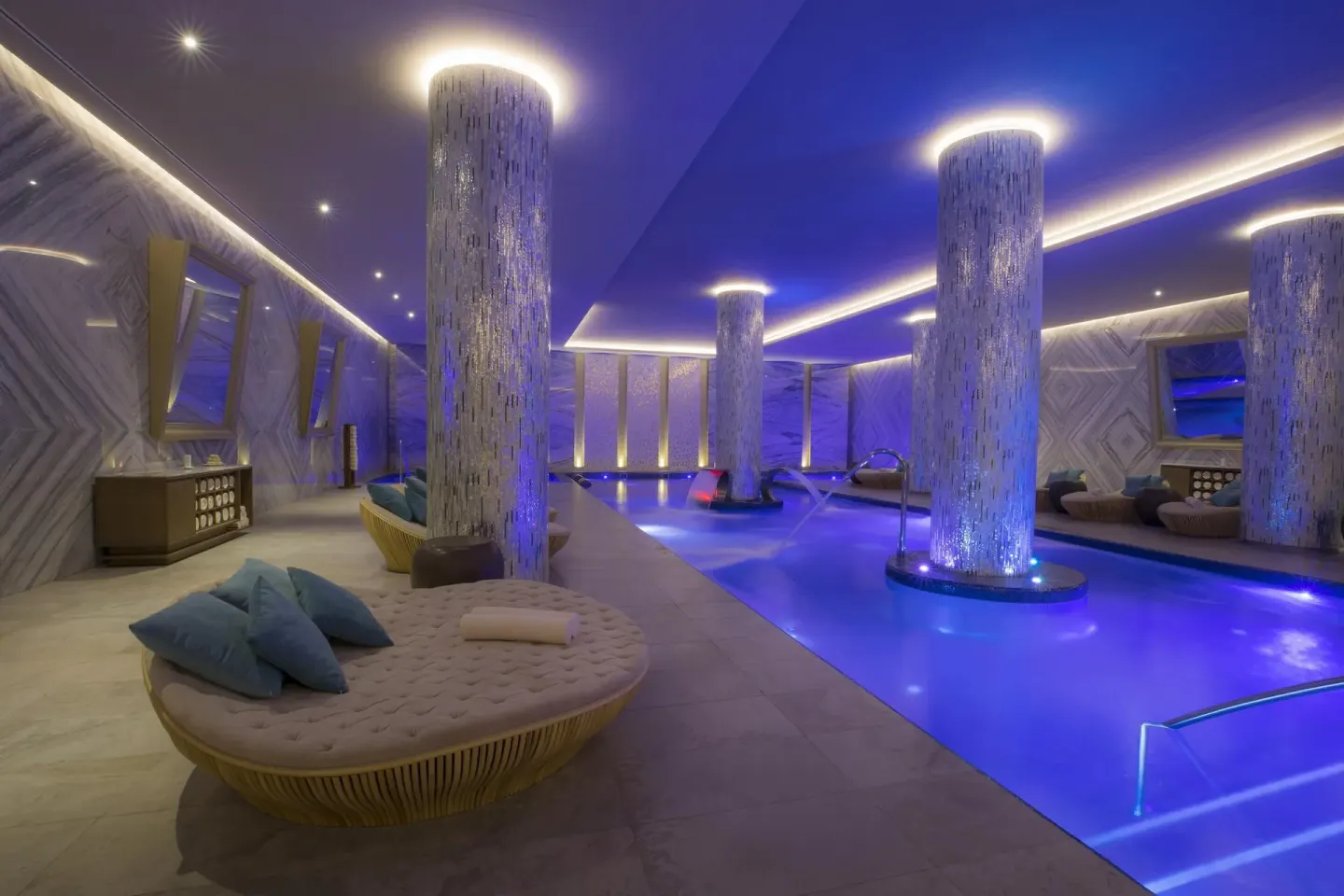 Indoor spa pool with illuminated columns and lounge beds at Moon Palace The Grand Cancun.