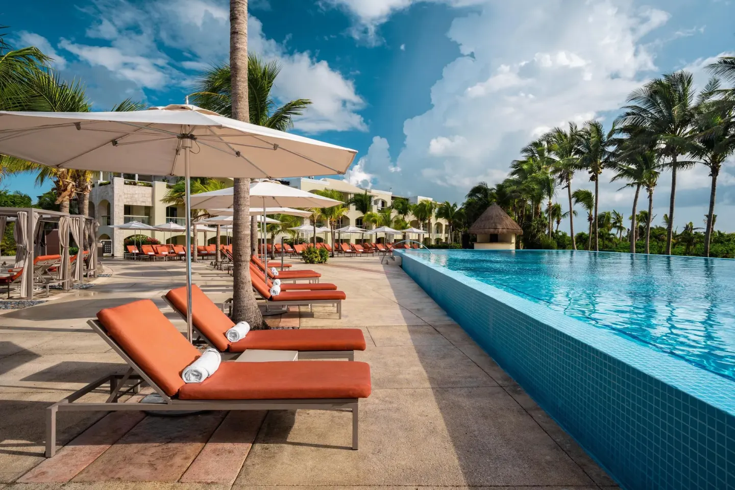 Infinity-edge pool with shaded loungers and palms at Moon Palace The Grand Cancun.