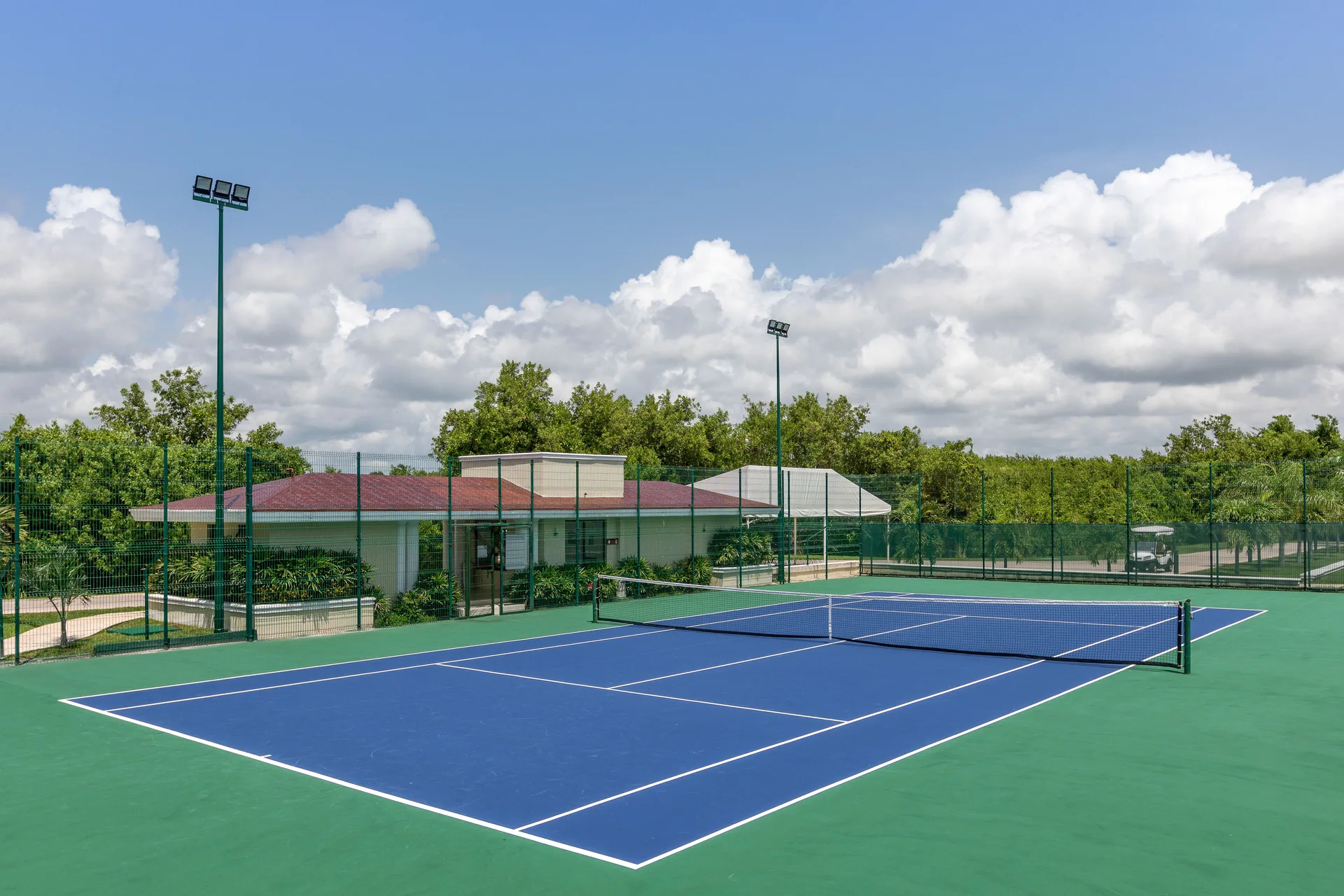 Outdoor tennis court under a cloudy blue sky at Moon Palace The Grand Cancun.