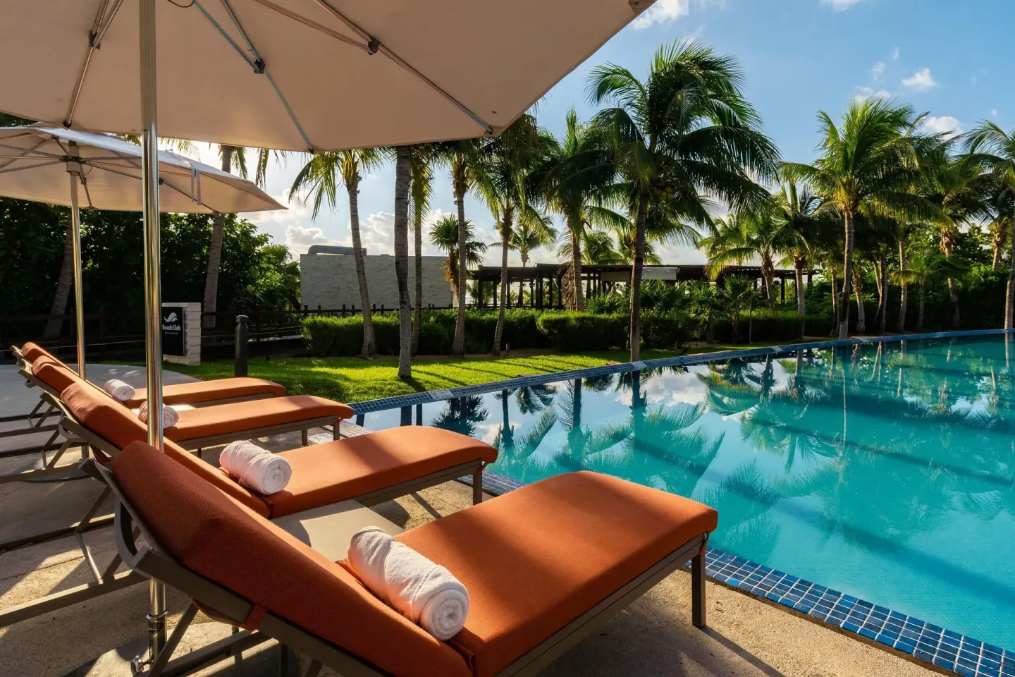 Poolside loungers with orange cushions and umbrellas at Moon Palace The Grand Cancun.