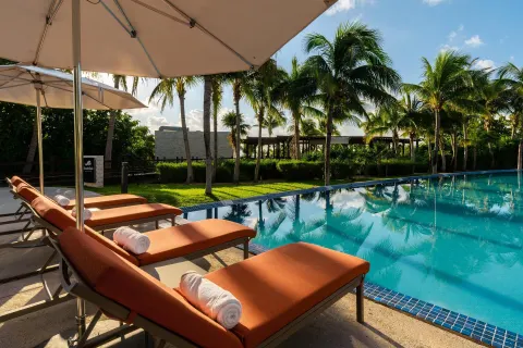 Poolside loungers with orange cushions and umbrellas at Moon Palace The Grand Cancun.