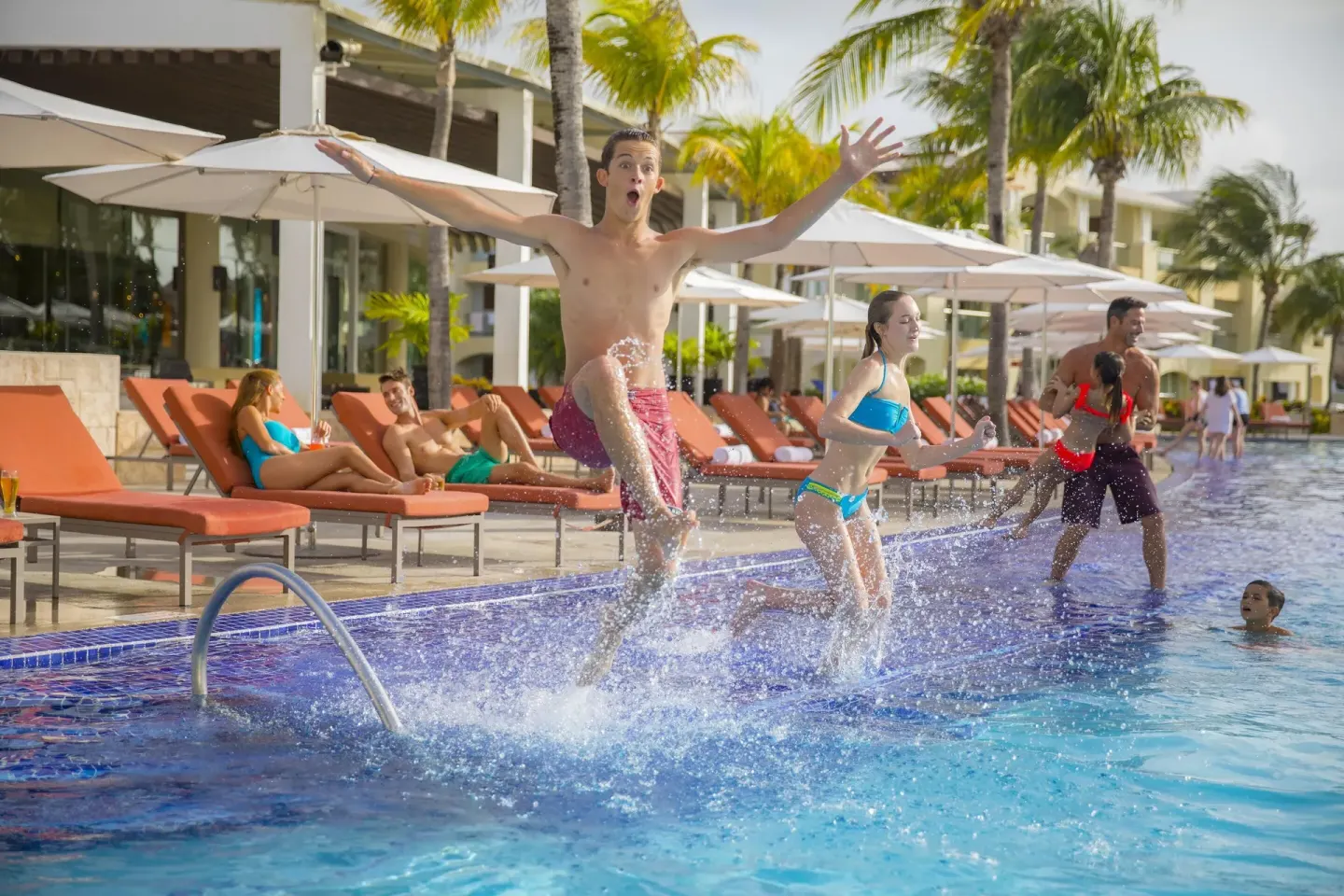 Children splashing beside pool loungers and umbrellas at Moon Palace The Grand Cancun.