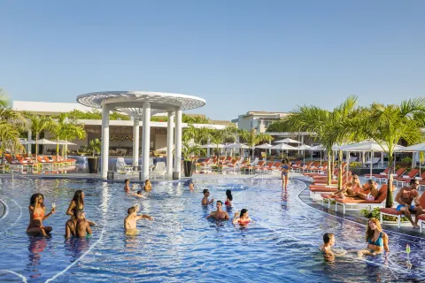 Resort pool with swimmers, cabanas, palms, and loungers at Moon Palace The Grand Cancun.