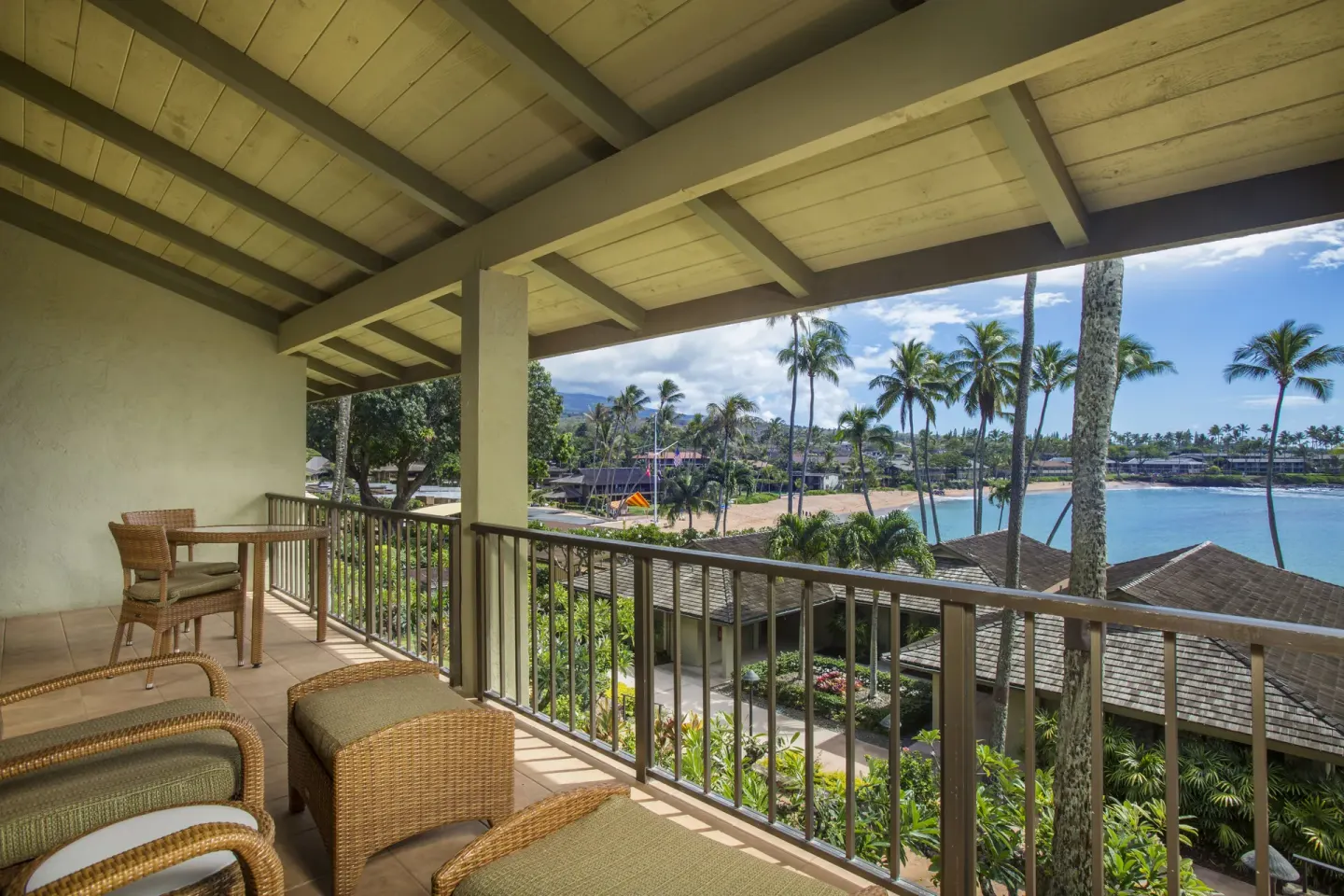 Covered lanai with wicker seating and bay views at Napili Kai Beach Resort.