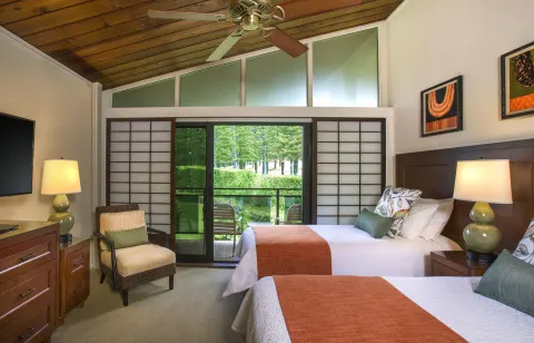 Guest room at Napili Kai Beach Resort with two beds, vaulted wood ceiling, and balcony doors.