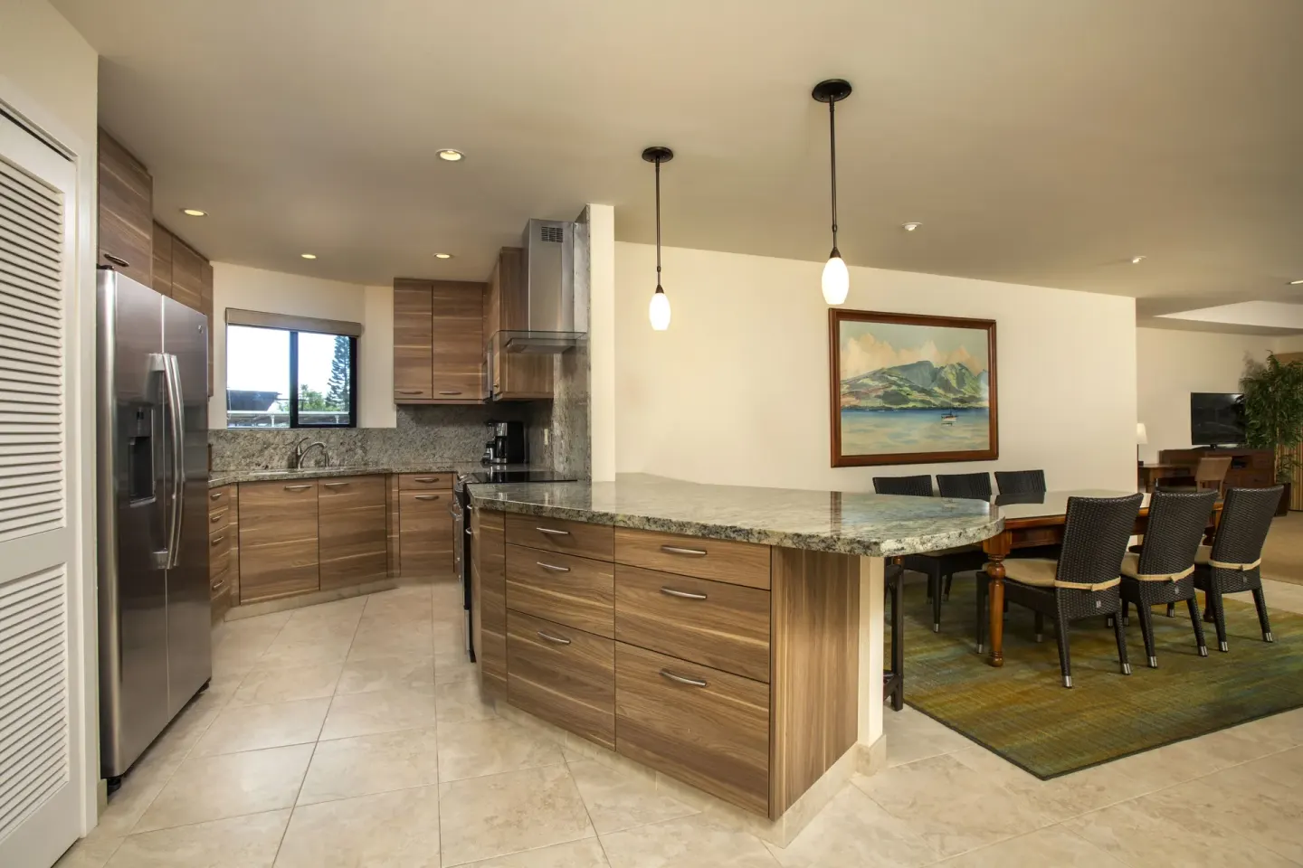 Full kitchen and dining area at Napili Kai Beach Resort with wood cabinetry and stone counters.