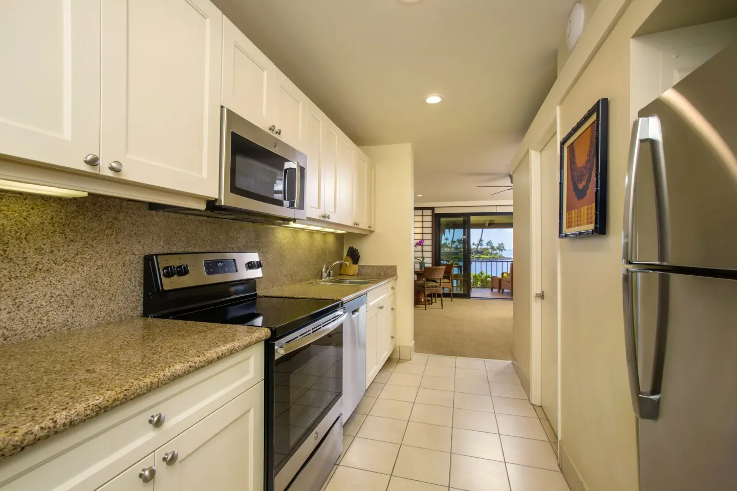 Deluxe Room kitchen with stove, microwave, refrigerator, and balcony beyond at Napili Kai Beach Resort.