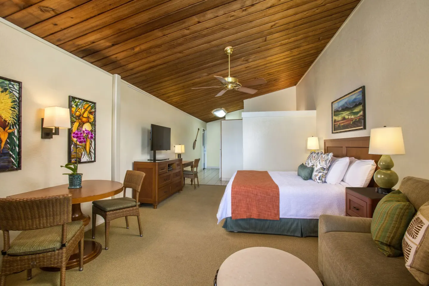 Deluxe Room with king bed, sofa, dining table, and vaulted wood ceiling at Napili Kai Beach Resort.