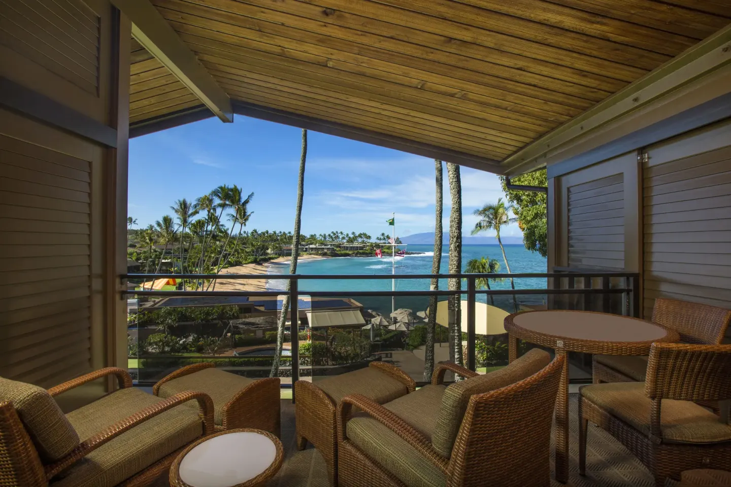 Deluxe Room lanai with wicker seating and ocean view at Napili Kai Beach Resort.