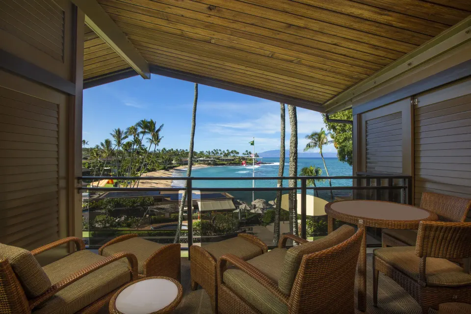 Deluxe Room lanai with wicker seating and ocean view at Napili Kai Beach Resort.