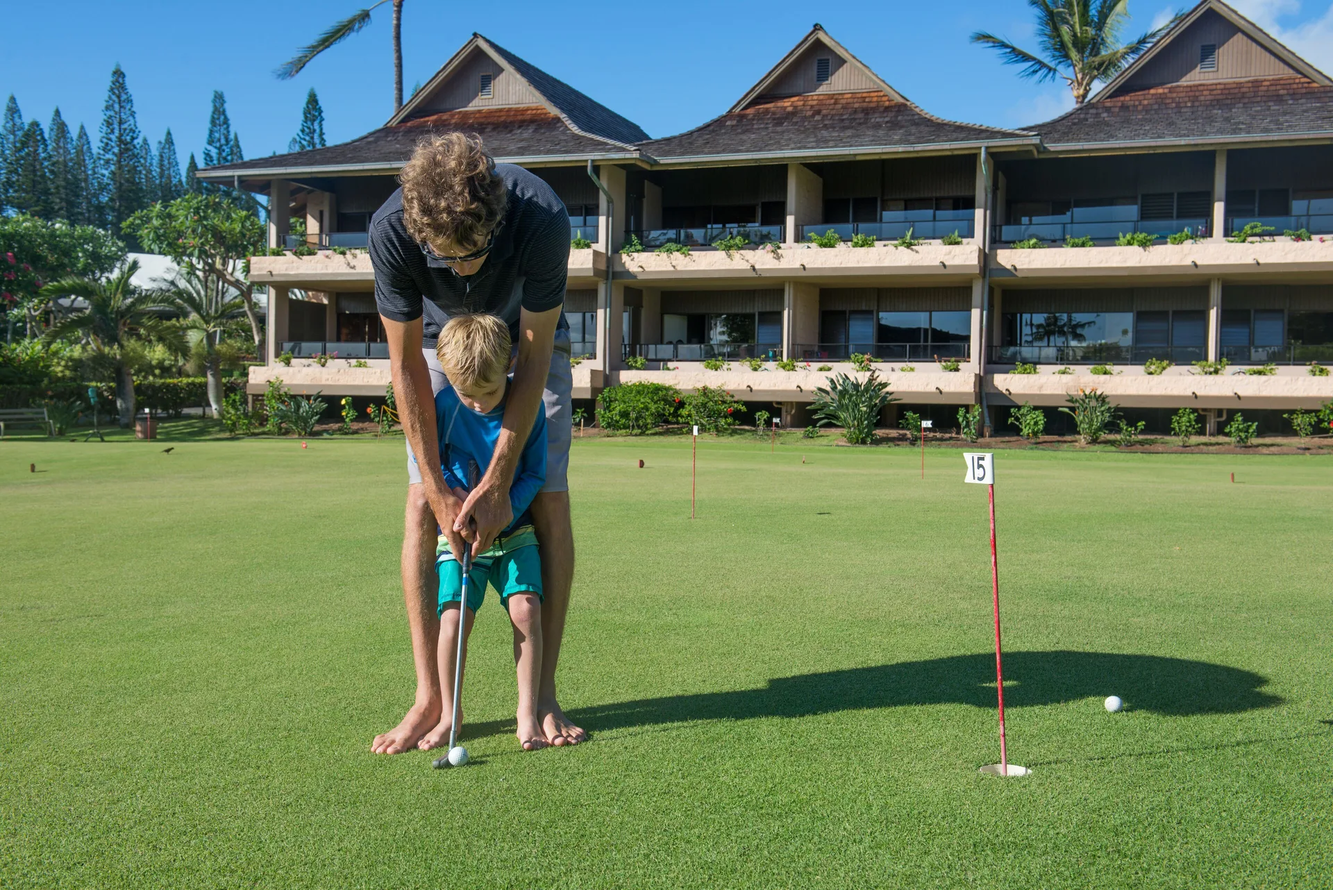 Family putting on a green outside Napili Kai Beach Resort guest buildings.