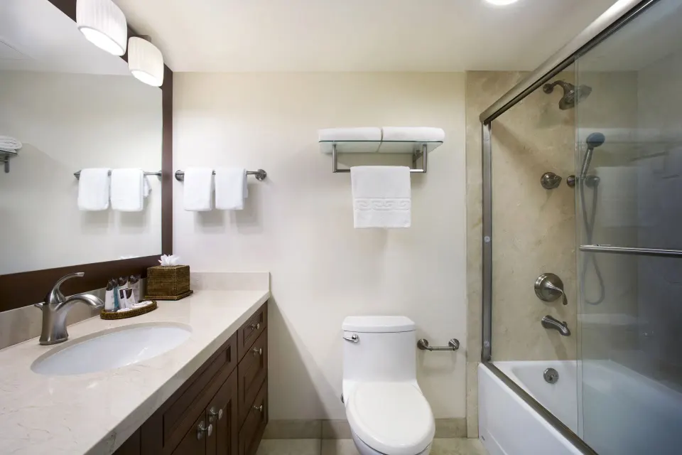 Studio bathroom with vanity, towels, toilet, and glass shower-tub at Napili Kai Beach Resort.