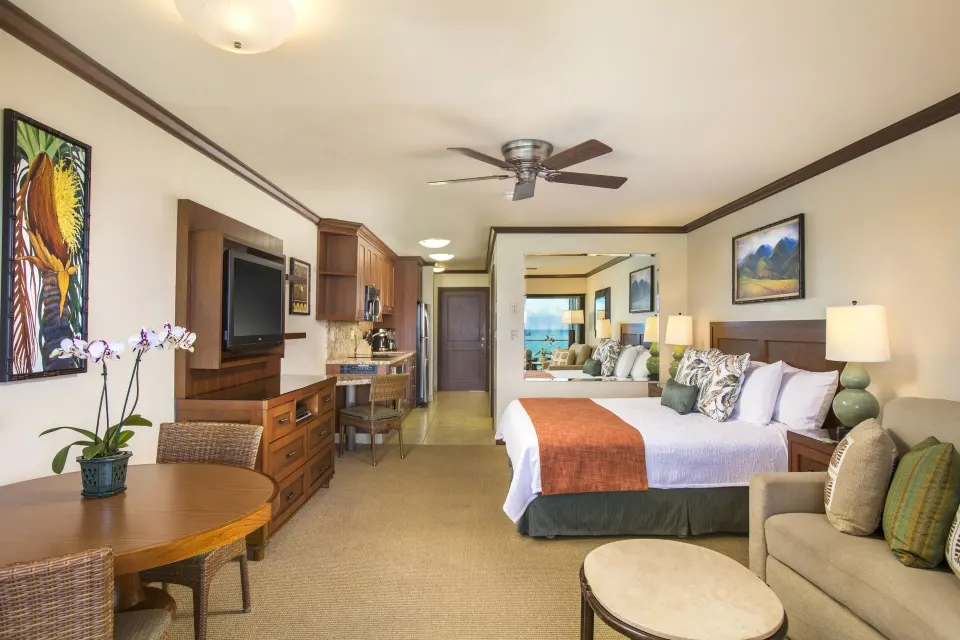 Oceanfront studio with king bed, sofa, dining table, and kitchenette at Napili Kai Beach Resort.