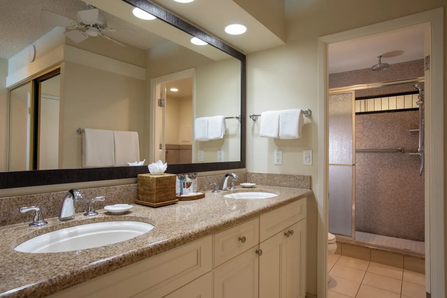 Bathroom vanity in an oceanfront suite at Napili Kai Beach Resort with two sinks and shower beyond.