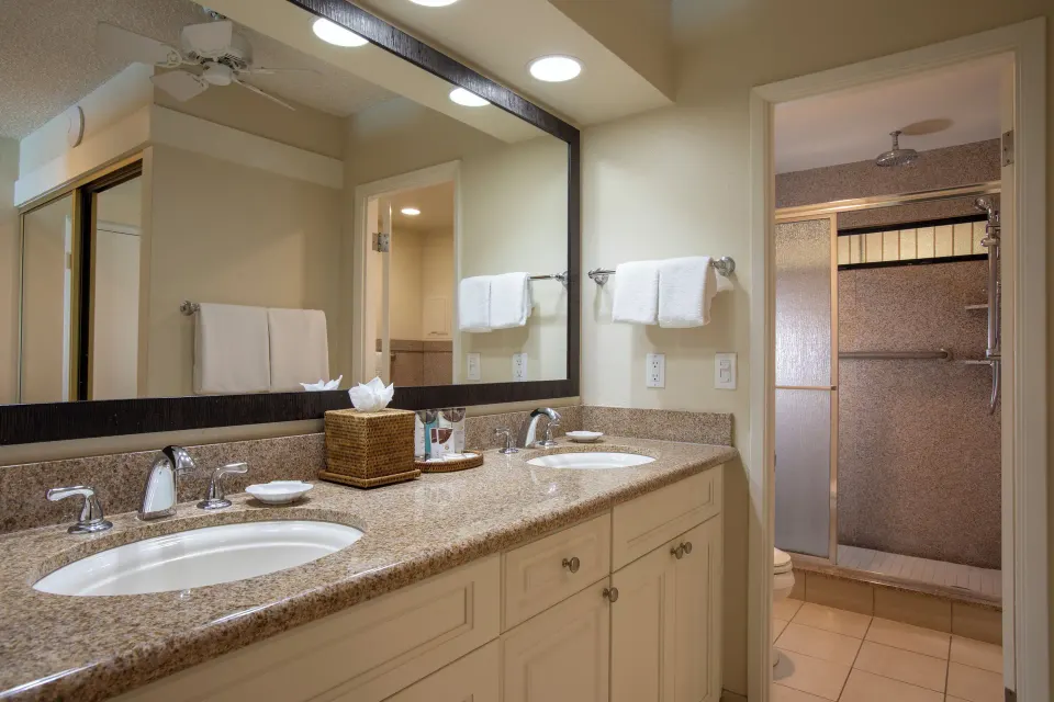 Bathroom vanity in an oceanfront suite at Napili Kai Beach Resort with two sinks and shower beyond.