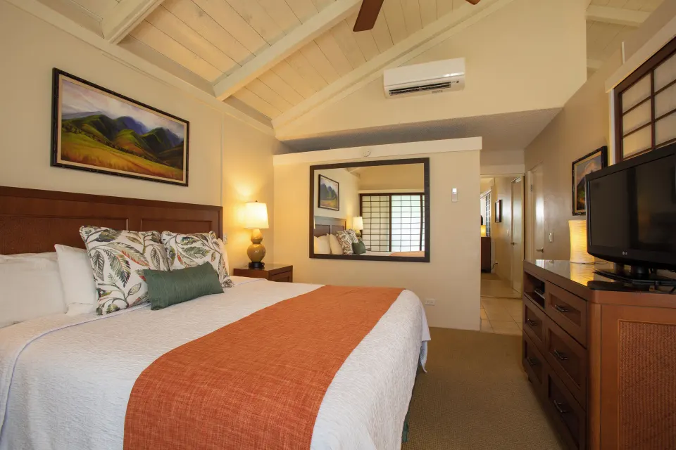 King bedroom in an oceanfront suite at Napili Kai Beach Resort with vaulted ceiling and dresser.