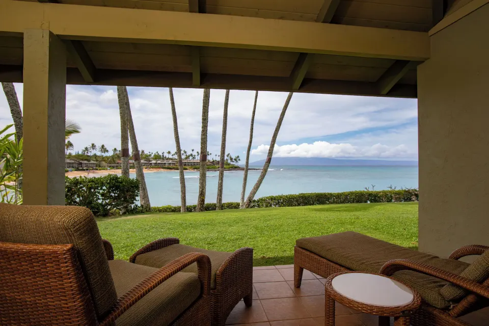 Oceanfront lanai view from a suite at Napili Kai Beach Resort with wicker chairs and bay beyond.