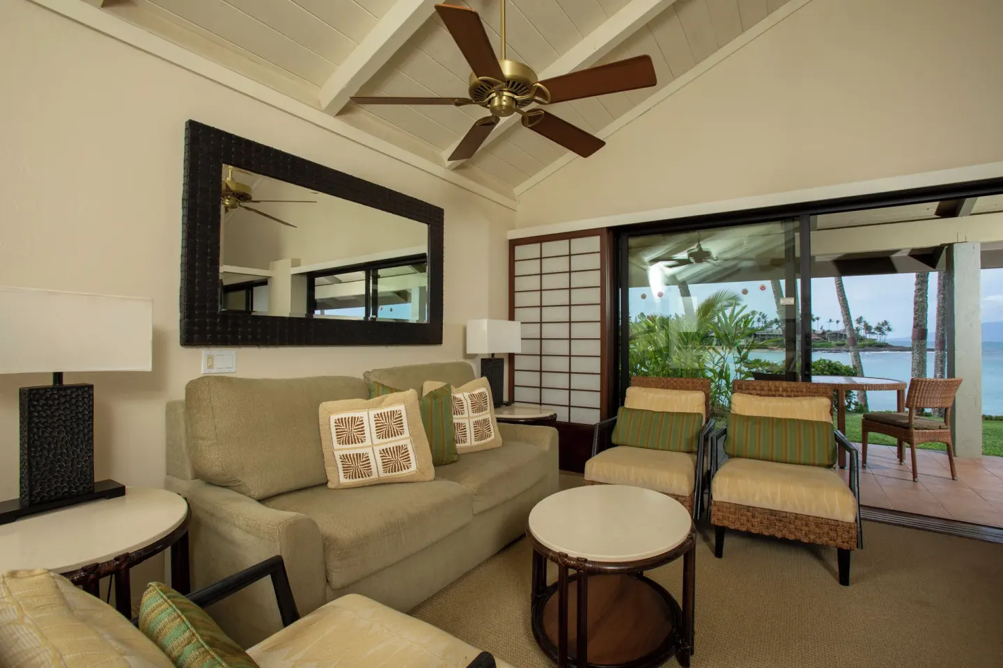 Living room in an oceanfront suite at Napili Kai Beach Resort with sofa, chairs, and lanai view.