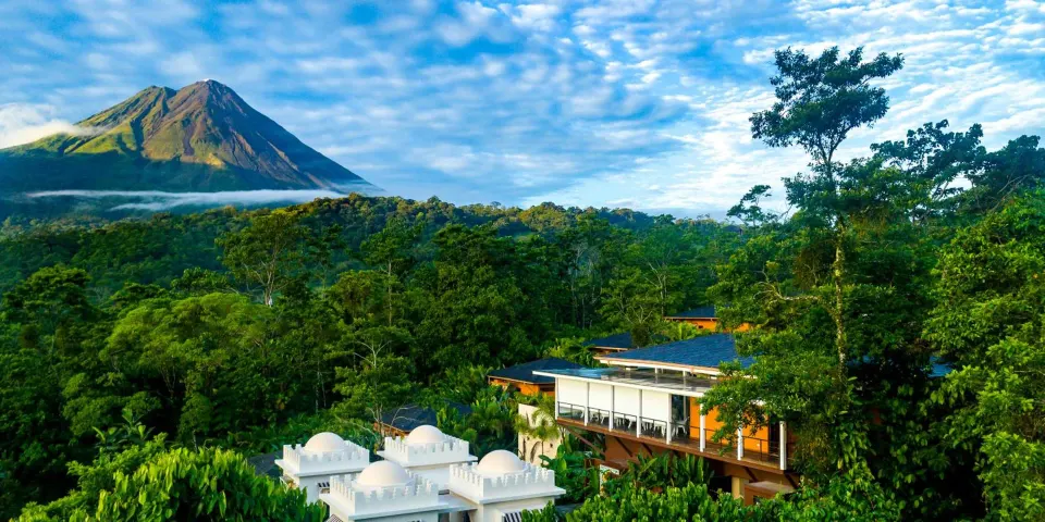 Arenal Volcano rises beyond rainforest and resort rooftops at Nayara Springs.