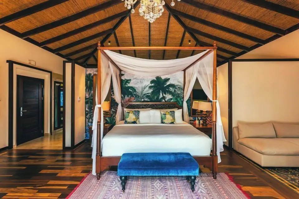 Canopy king bed with blue bench and vaulted wood ceiling at Nayara Springs.