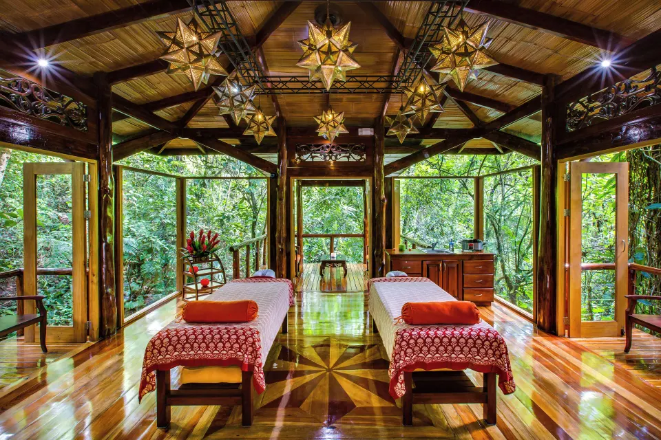 Spa treatment room with two massage tables and forest views at Nayara Springs.