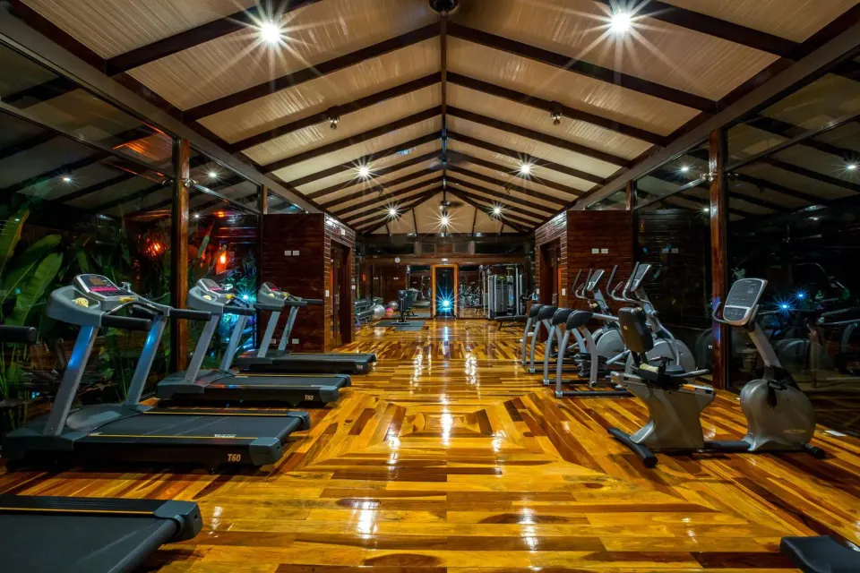 Treadmills and cardio machines line a polished wood fitness room at Nayara Springs.