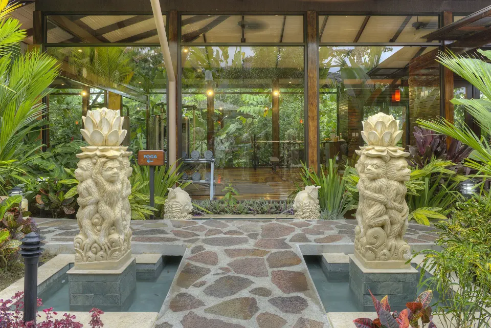 Carved statues, water features, and glass doors mark an entrance at Nayara Springs.