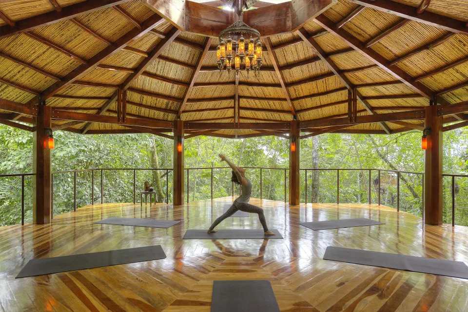 Open-air yoga pavilion with mats and a person stretching at Nayara Springs.