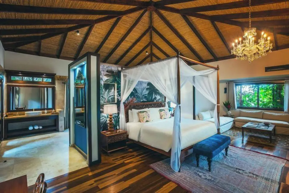 Open-plan suite with canopy king bed and bathroom at Nayara Springs.