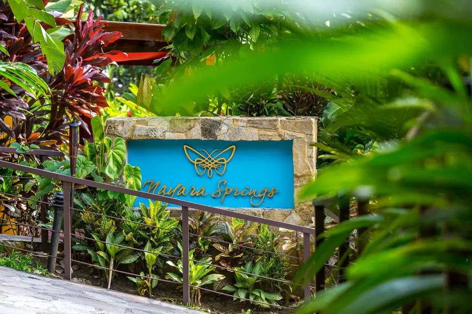 Nayara Springs entrance sign framed by tropical foliage.