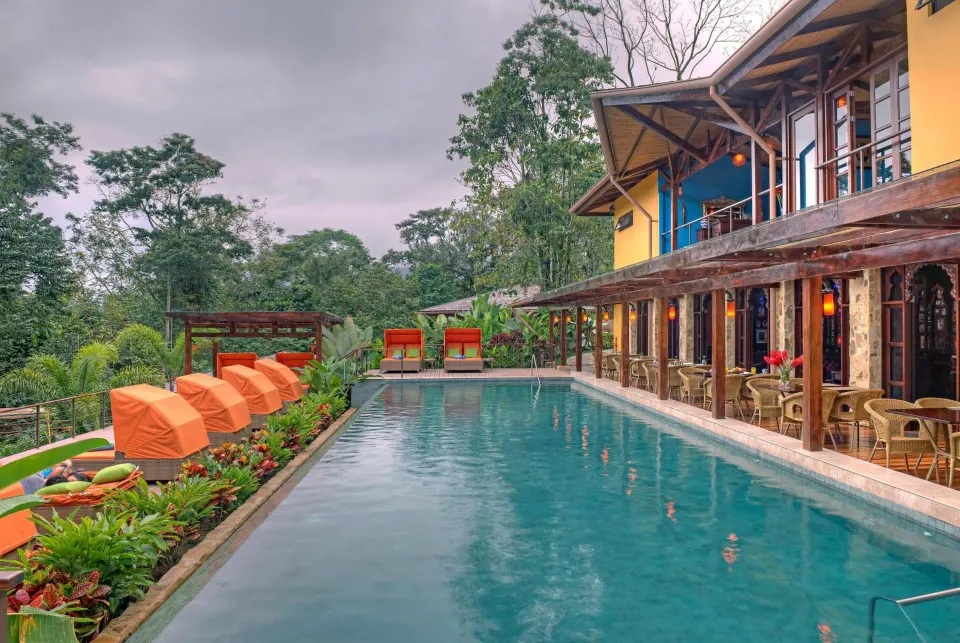 A long pool with orange loungers sits beside a two-story building at Nayara Springs.