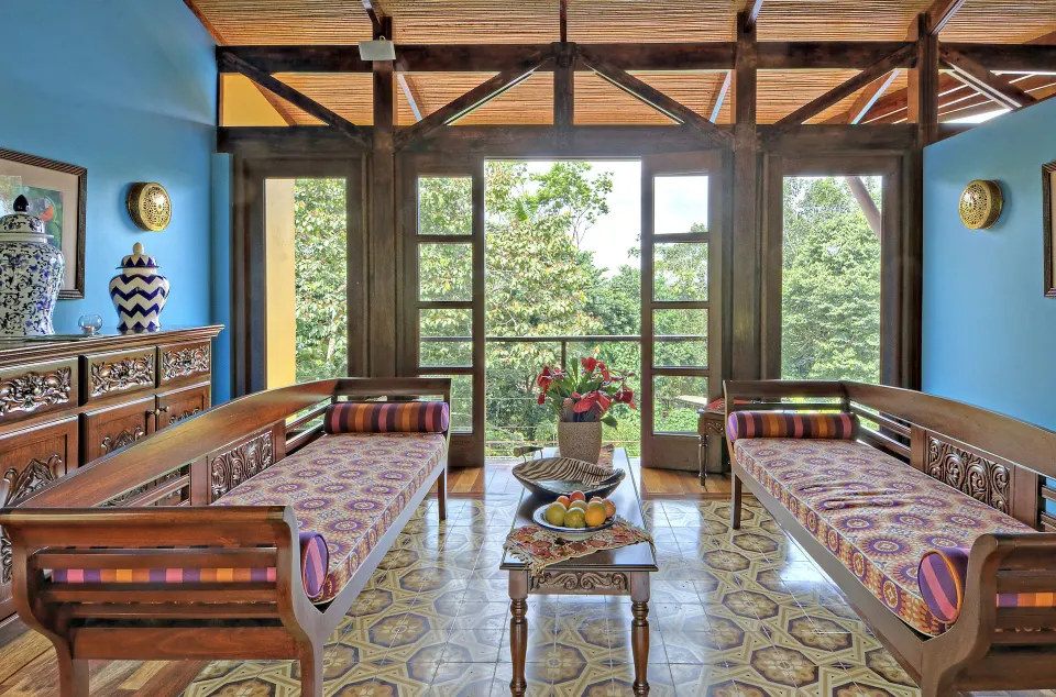 Relaxation lounge with two daybeds, blue walls, and forest views at Nayara Springs.