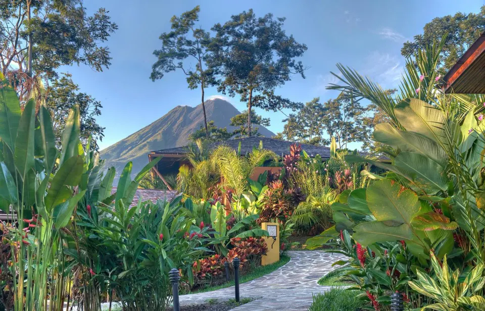 A garden path leads through tropical plants toward Arenal Volcano at Nayara Springs.