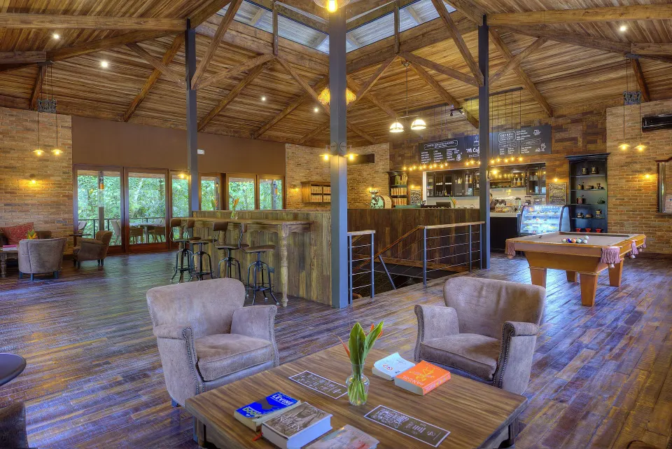 A coffee bar and lounge with armchairs and a pool table is shown at Nayara Springs.