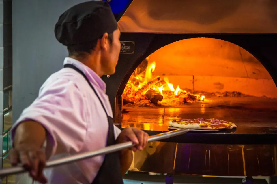 A chef slides a pizza into a wood-fired oven at Nayara Springs.