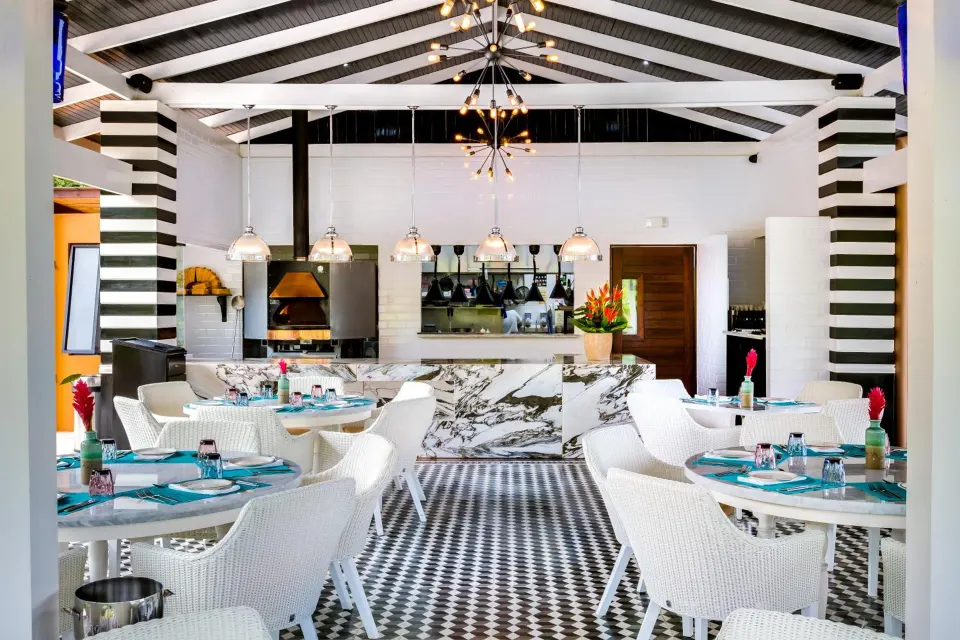 Bright restaurant dining room with open kitchen at Nayara Springs.