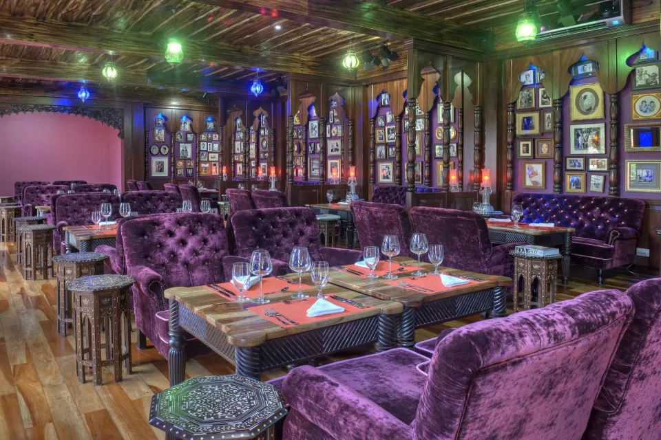 Plush purple dining room with set tables at Nayara Springs.