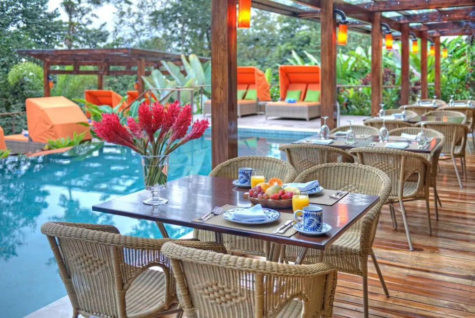 Poolside dining terrace with wicker chairs at Nayara Springs.