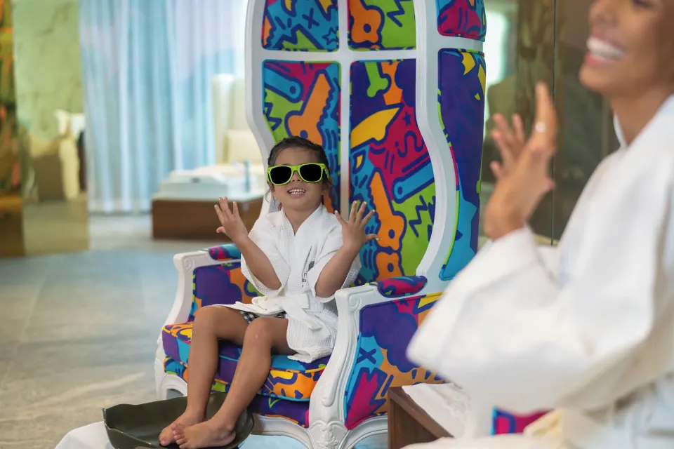 A child in a robe sits on a colorful spa chair at Nickelodeon Hotels & Resorts Riviera Maya.