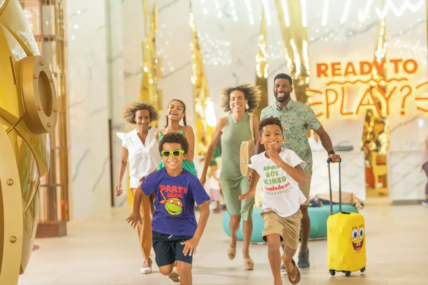 Family arriving in the lobby with children running at Nickelodeon Hotels & Resorts Riviera Maya.