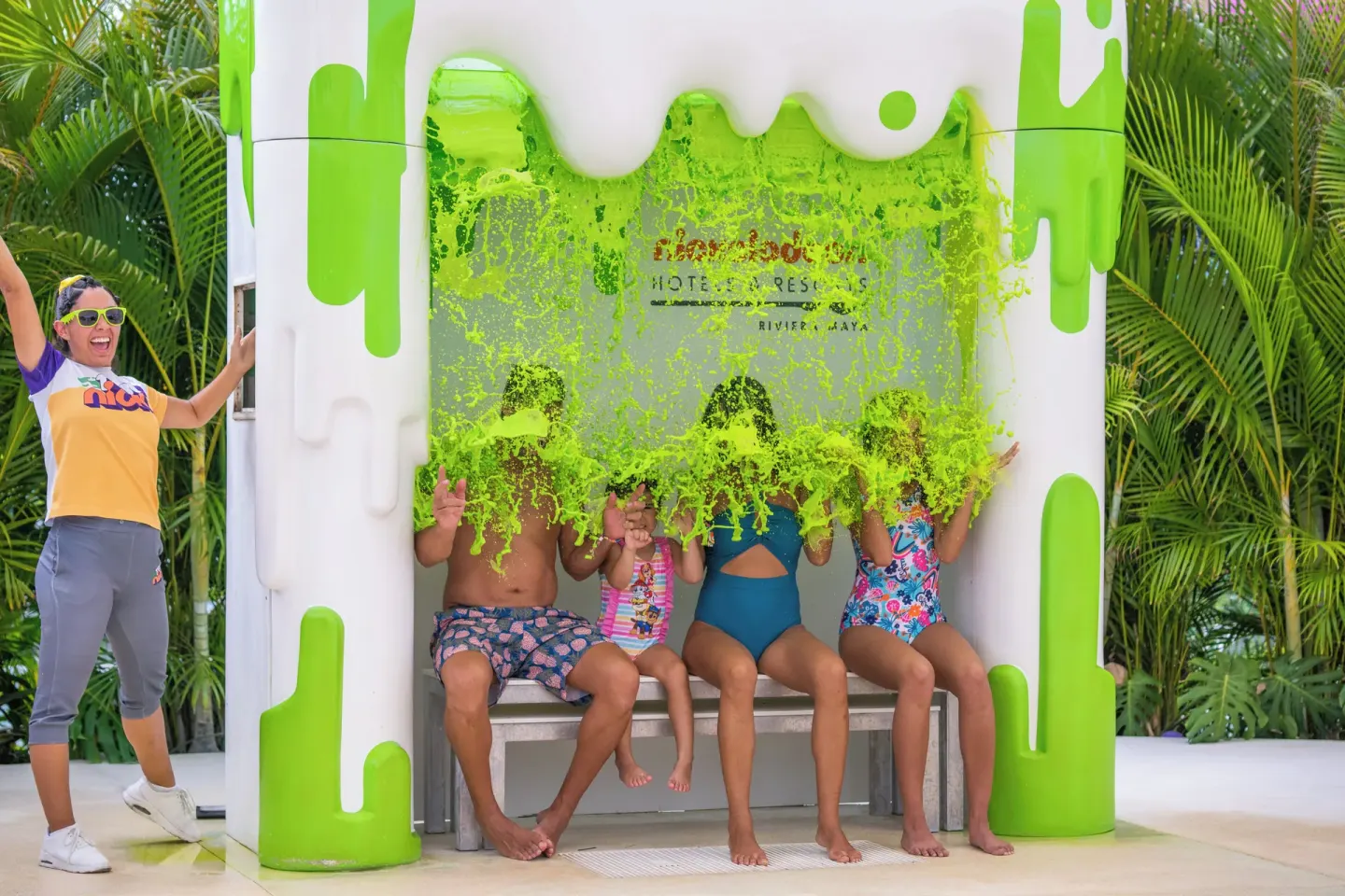 A family sits beneath a green slime splash at Nickelodeon Hotels & Resorts Riviera Maya.