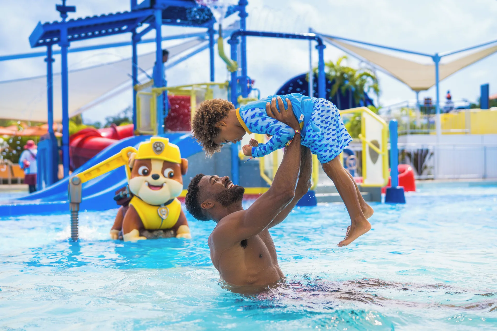 Adult lifting a child in the splash pool at Nickelodeon Hotels & Resorts Riviera Maya.