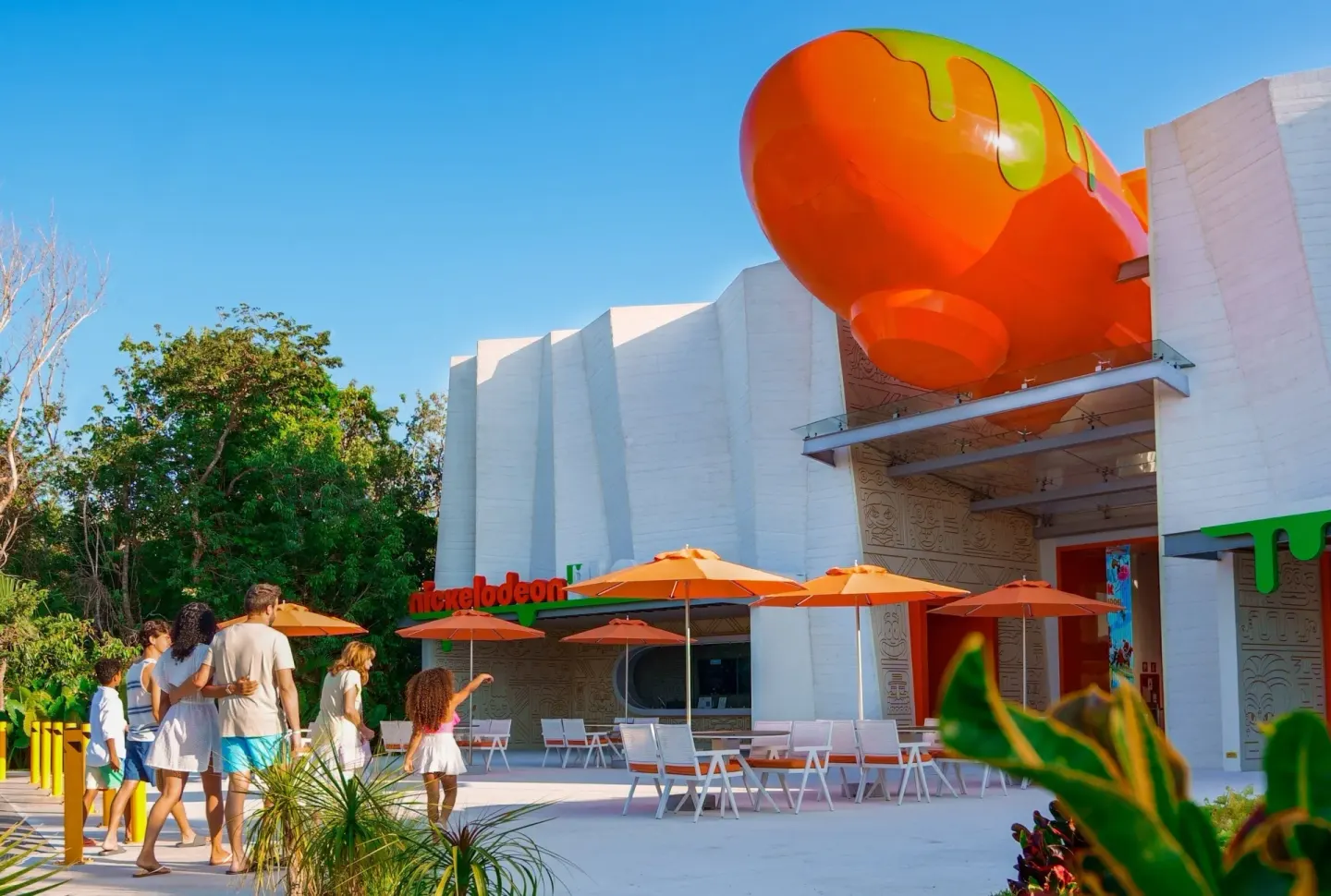 Family walks toward a building with an orange blimp at Nickelodeon Hotels & Resorts Riviera Maya.