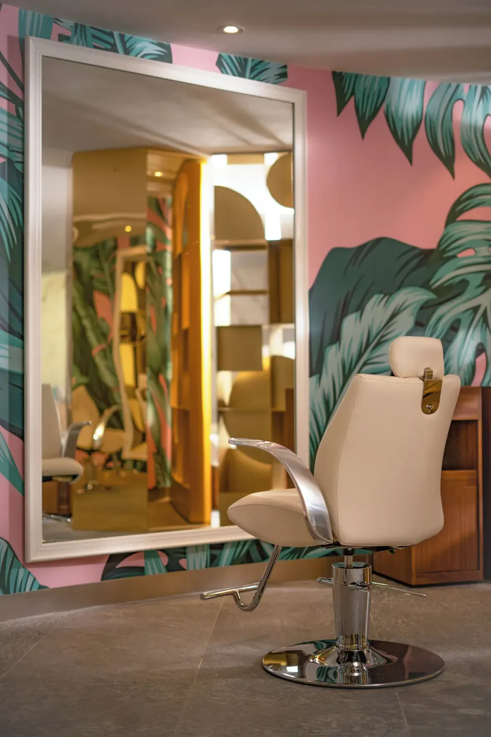 A salon chair and large mirror stand against leafy pink wallpaper at Nickelodeon Hotels & Resorts Riviera Maya.