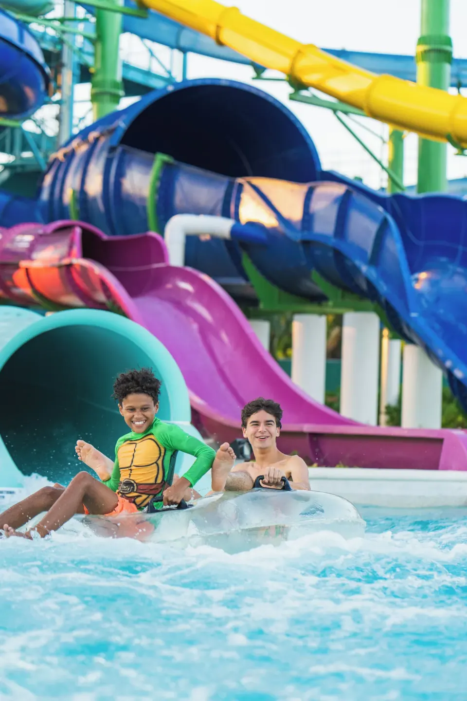 Two guests ride an inner tube past colorful waterslides at Nickelodeon Hotels & Resorts Riviera Maya.