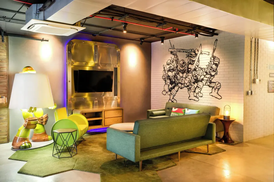 Lair Suite living room with sofa, TV wall, and turtle-themed décor at Nickelodeon Hotels & Resorts Riviera Maya.
