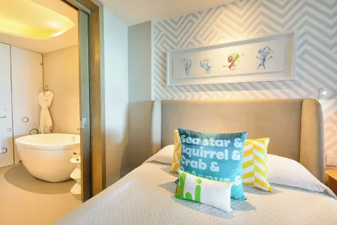 Oceanfront Swim-Up Suite bed beside open bathroom at Nickelodeon Hotels & Resorts Riviera Maya.