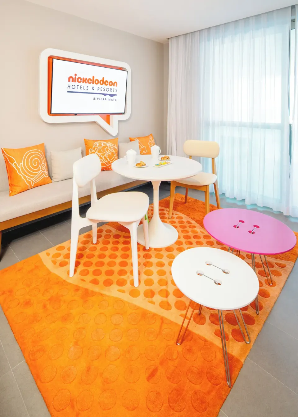 Oceanfront Swim-Up Suite dining corner by sheer curtains at Nickelodeon Hotels & Resorts Riviera Maya.